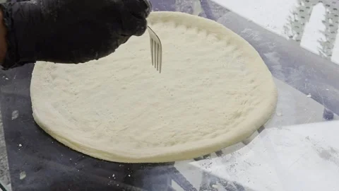 Hand using a fork to prick holes on pizza dough. Stock Footage 323866509
