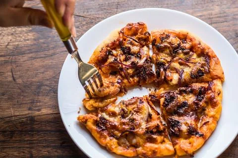Hand using a fork to take a slice of delicious homemade pizza Stock Photos