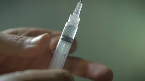 Hand using hypodermic syringe and spraying out liquid in slow motion Stock Footage 57798754