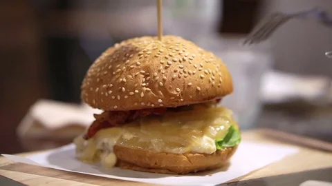 Hand using knife and fork cutting bun and beef burger Stock Footage 70098094