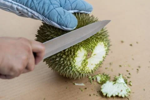 Hand using knife to peel durian shell which has a lot of thorns..Tropical sea Stock Photos