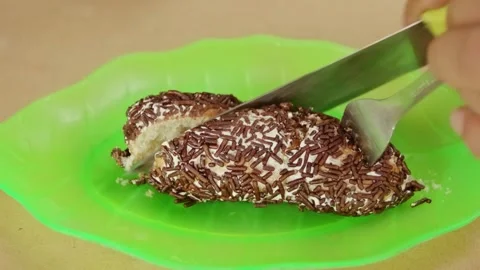 Hand using knife slicing sweet bread topped with chocolate sprinkles on gre.. Stock Footage 324819498