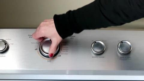 Hand using the knobs and button of the electric clothes dryer appliance. Stock Footage 170919011
