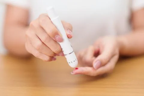 Hand using lancet pen on finger with Blood drop glucose testing or Diabetes.. Stock Photos