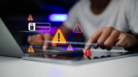 Hand using laptop and tablet with warning triangle alert icons. Concept of .. Stock Photos