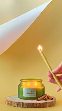 Hand using a long wax taper candle to light a candle in a ribbed green jar. Stock Photos