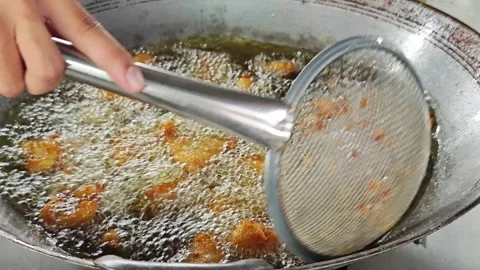 Hand using a mesh strainer to scoop food from hot frying oil. Stock Footage 342739019