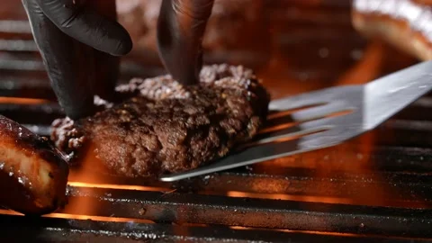 Hand with Spatula and BBQ Grill with Meat and Vegetables Stock