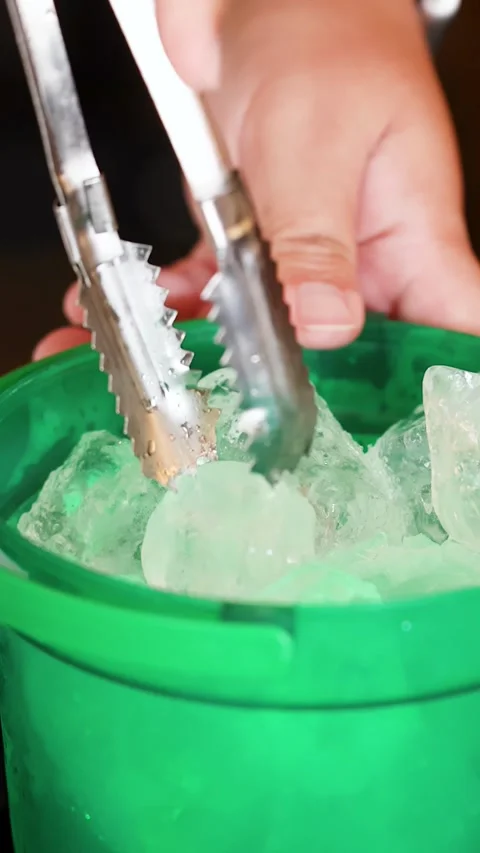 Hand Using Metal Tongs to Grab Ice from Green Bucket Stock Footage 344514720