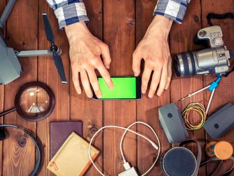 Hand using a mobile phone on the table with diffrent things, supplies and stu Stock Photos