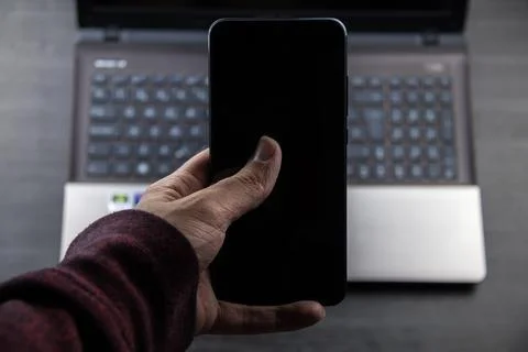 Hand using a modern mobile and a laptop background Stock Photos