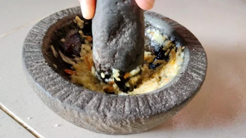 Hand Using a Mortar and Pestle to Grind Fresh Ingredients for Cooking Stock Footage 305036682