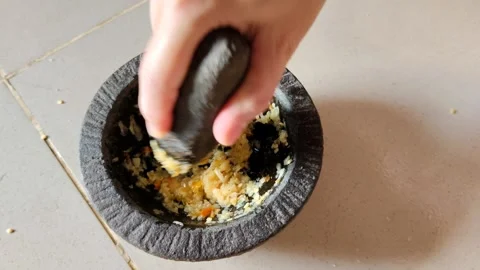 Hand Using a Mortar and Pestle to Grind Fresh Ingredients for Cooking Stock Footage 305036684