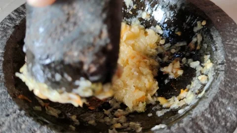 Hand Using a Mortar and Pestle to Grind Fresh Ingredients for Cooking Stock Footage 305037251