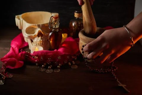 Hand using mortar Scary still life with potions, skull, mortar, vintage bottl Stock Photos