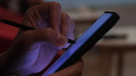 Hand using or Writing stylus on smartphone screen in low light Stock Footage 332106756