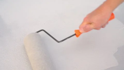 Hand using paint roller to apply white waterproof coating on a textured roo.. 스톡 동영상 333051466
