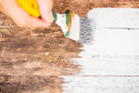 Hand using paintbrush decorating or painting old wood brown color to white co Stock Photos