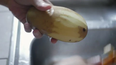 Hand using peeler to peel potato skin preparing for cooking Stock Footage 196173317
