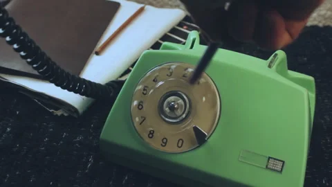 Hand using pen to turn vintage green rotary telephone dial Stock Footage 337977160