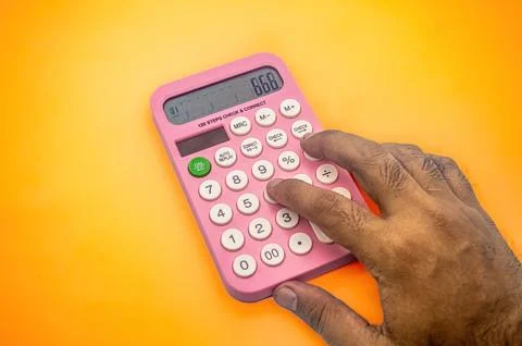 A hand using a pink calculator on a vibrant orange background. The calculat.. Stock Photos