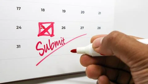 Hand using a red marker to write Submit and cross out a date on a wall cale.. Stock Photos