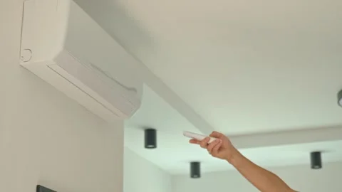 Hand using remote control to adjust temperature on air conditioner at home Stock Footage 312573663