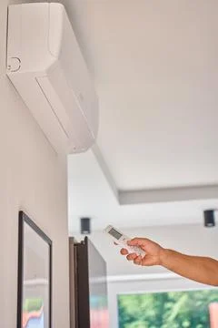 Hand using remote control to adjust temperature on air conditioner at home Foto stock