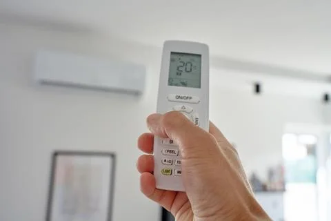 Hand using remote control to adjust temperature on air conditioner Foto stock