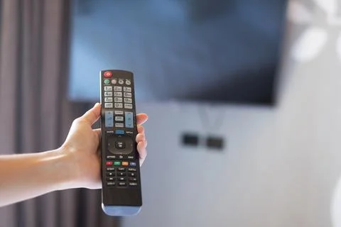 Hand using remote controller for adjust Smart TV inside the modern room at ho Foto stock