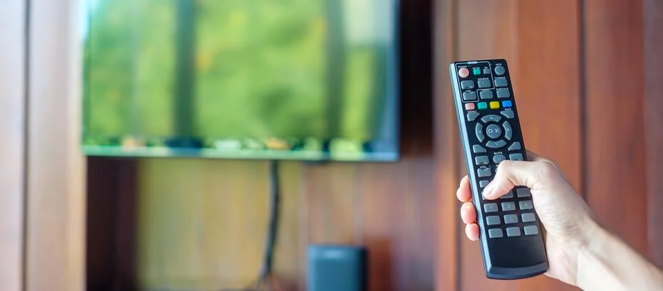 Hand using remote controller for adjust Smart TV inside the modern room at ho Stock Photos