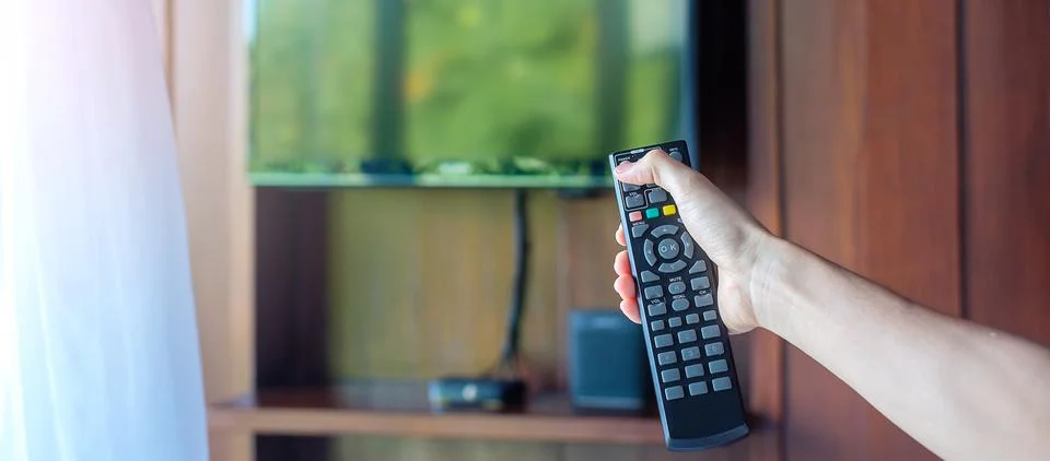 Hand using remote controller for adjust Smart TV inside the modern room at ho Foto stock