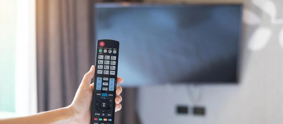 Hand using remote controller for adjust Smart TV inside the modern room at .. Stock Photos