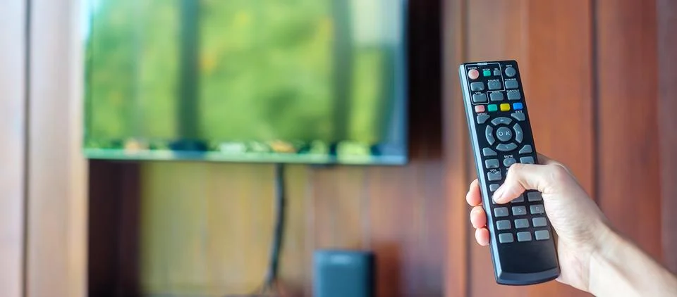 Hand using remote controller for adjust Smart TV inside the modern room at .. Stock Photos