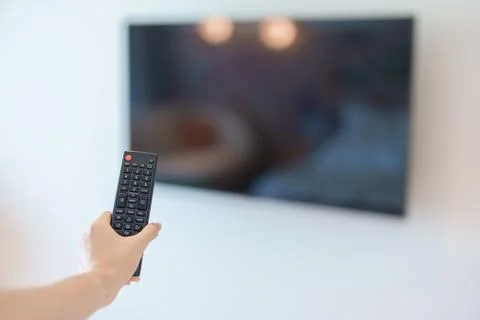 Hand using remote controller press button for adjust Smart TV in modern roo.. Stock Photos