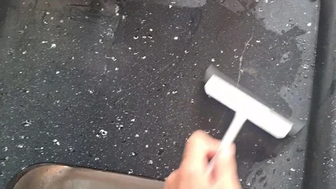 Hand using a rubber squeegee cleaning dark stone surface video footage Video stock 339247379