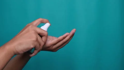 Hand using sanitizer or spray alcohol bottle isolated blue background 库存影片 275872484