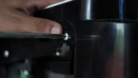 Hand using a screwdriver to tighten a screw on a black machine, Hand tighte.. Stock Footage 338319451