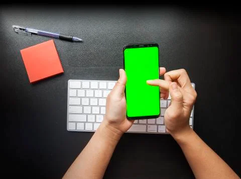 Hand using the smart phone with chroma screen on desk with copy space Stock Photos