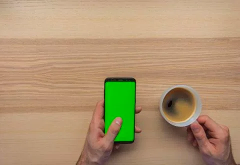 Hand using the smart phone with chroma screen on desk with coffee mug and cop Stock Photos
