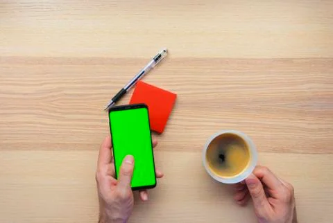 Hand using the smart phone with chroma screen on desk with coffee mug and cop Stock Photos