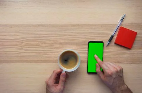 Hand using the smart phone with chroma screen on desk with coffee mug and cop Foto stock