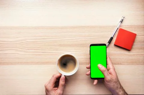 Hand using the smart phone with chroma screen on desk with coffee mug and cop Foto stock