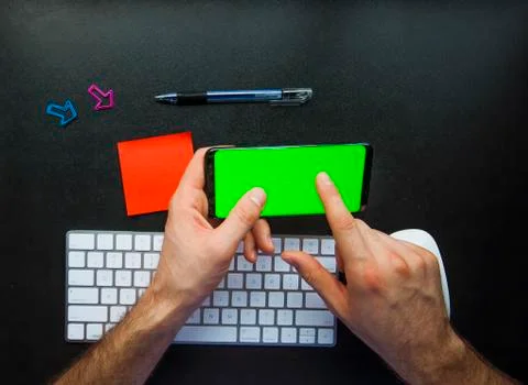 Hand using the smart phone on desk with keyboard and copy space Stock Photos