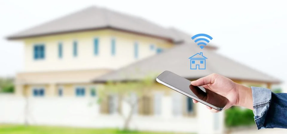 Hand using smart phone over blur house background, smart home control concept Stock Photos