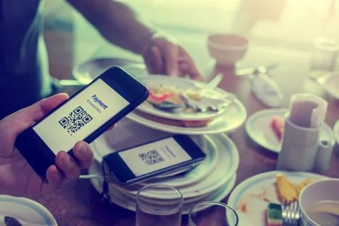 Hand using smart phone to scan QR code on tag with blurry many dishes after e Foto stock