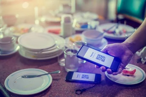 Hand using smart phone to scan QR code on tag with blurry many dishes after e 스톡 사진