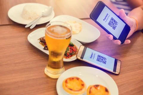 Hand using smart phone to scan QR code tag with blurry food, dessert and beer Stockfoto's