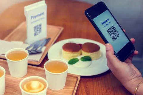 Hand using smart phone to scan QR code on tag with blurry dessert and tea in  Stockfoto's
