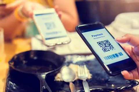 Hand using smart phone to scan QR code tag with blurry another smart phone an Stockfoto's
